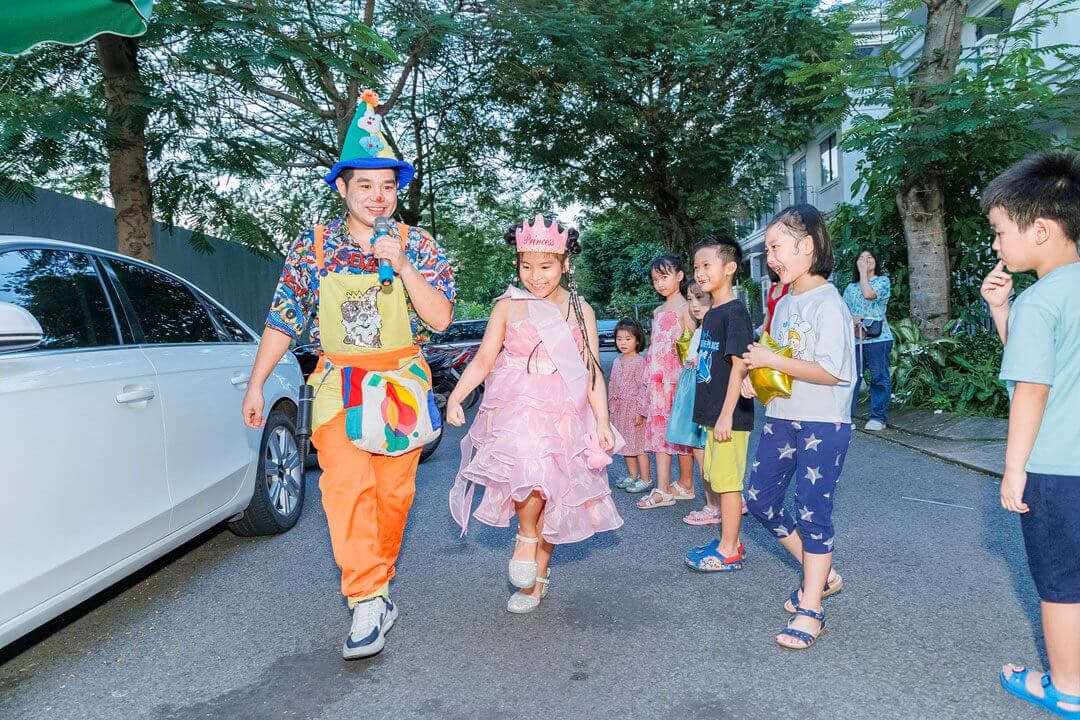 một nhóm trẻ em đang đi bộ trên phố cùng chú hề 